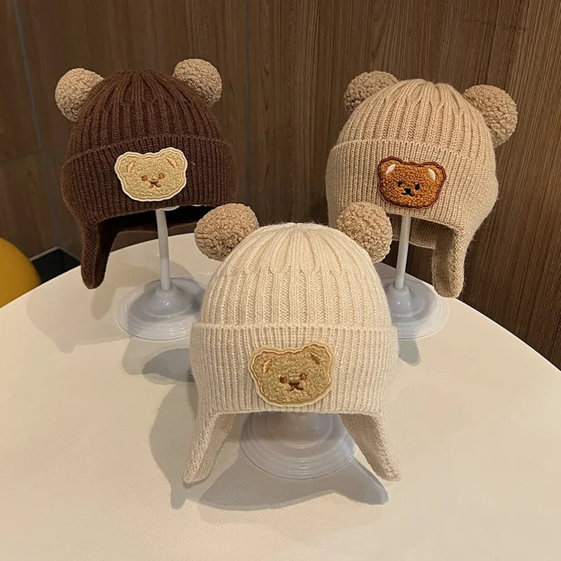 baby winter wool hat with bear ears in brown, beige, and cream colors displayed on a table