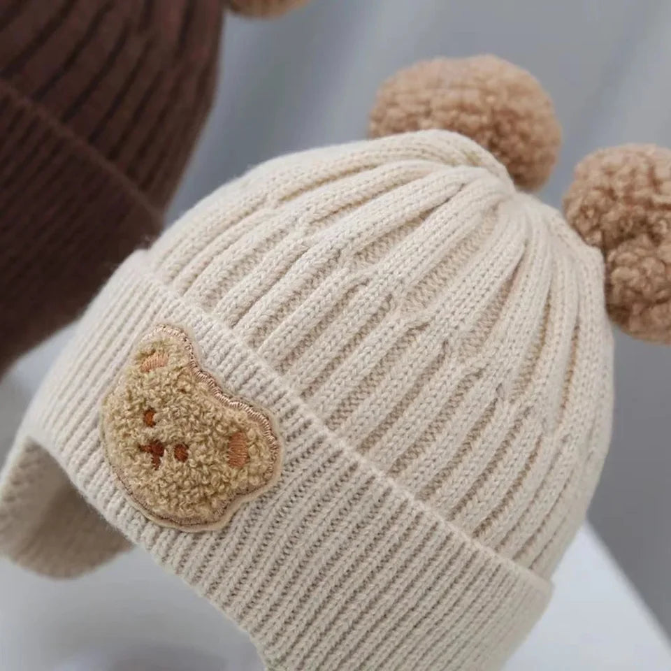 baby winter wool hat with bear ears featuring pom-poms and a cute bear face patch.